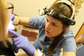 A dental student performs an oral cancer screening exam on a patient.